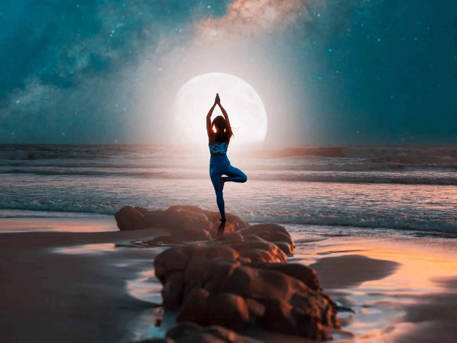 Frau in der Baumhaltung am Meer vor dem Vollmond und der Milchstrasse