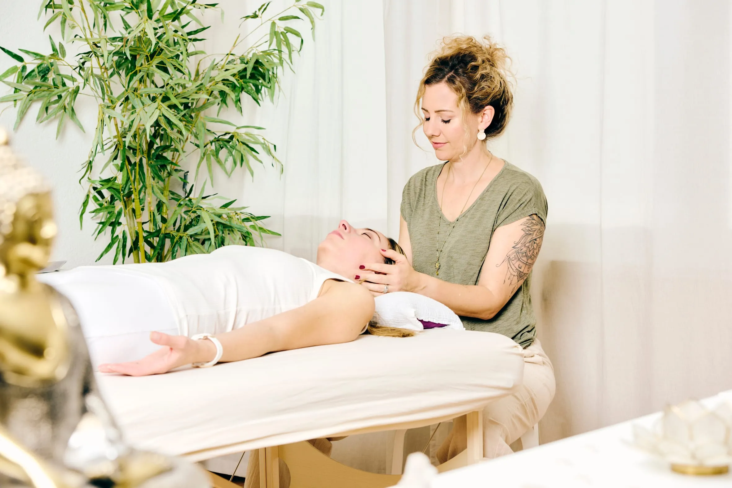 Nadine Caceda legt einer liegenden Person bei einer Reiki-Behandlung die Hände an den Kopf