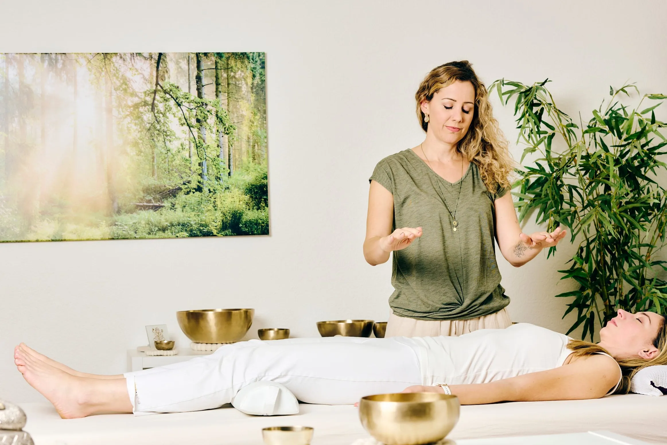 Nadine Caceda bei der Energiearbeit mit erhobenen Händen über einer liegenden Person