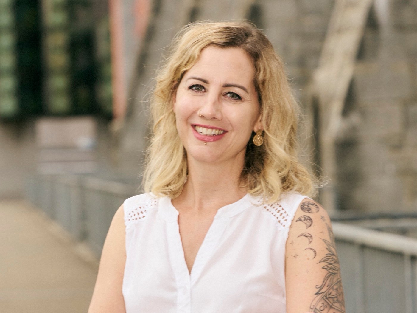 Nadine Caceda lächelnd an einem Brückengeländer