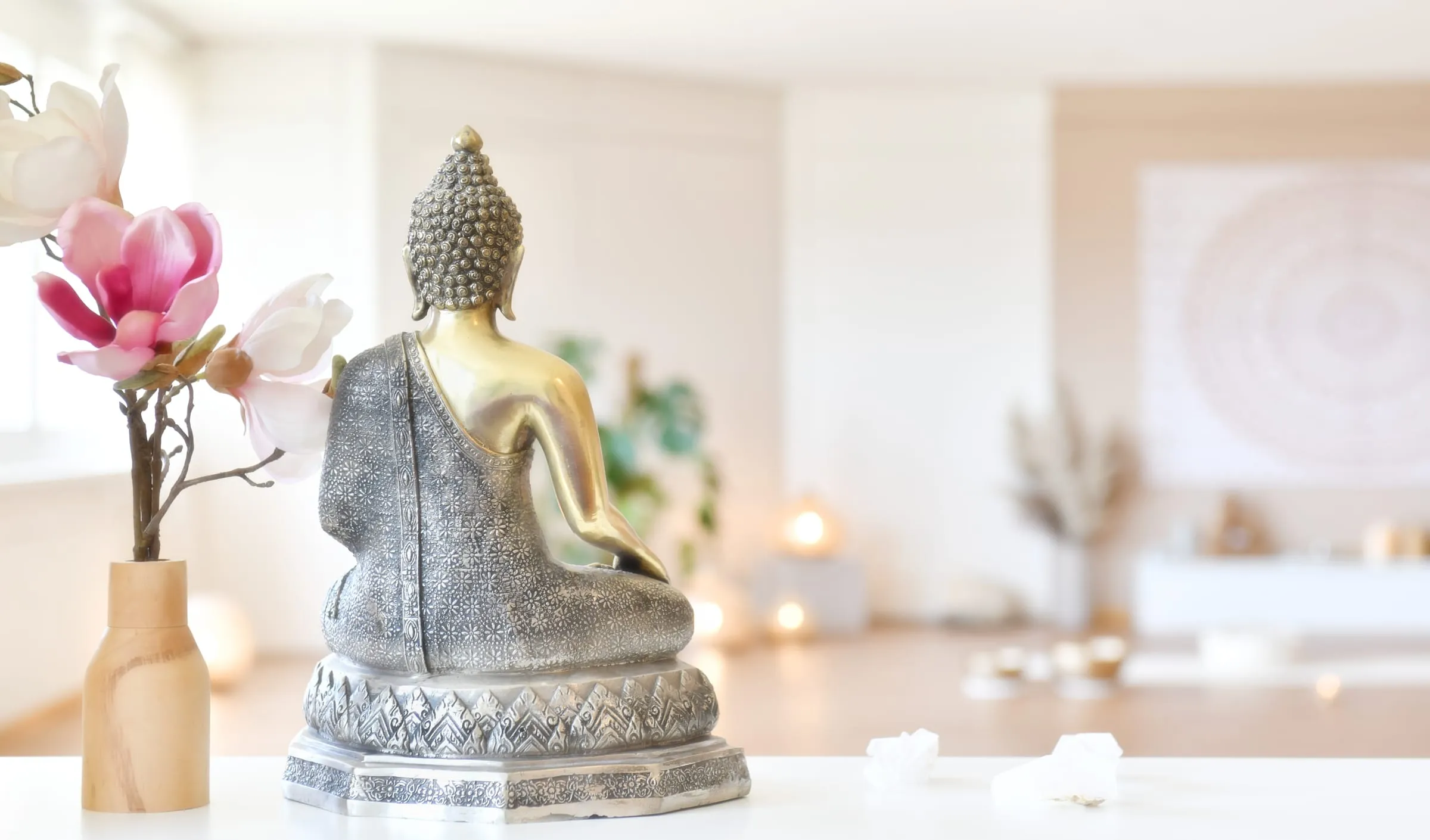 Buddha-Figur und Magnolienzweig im hellen Yogastudio